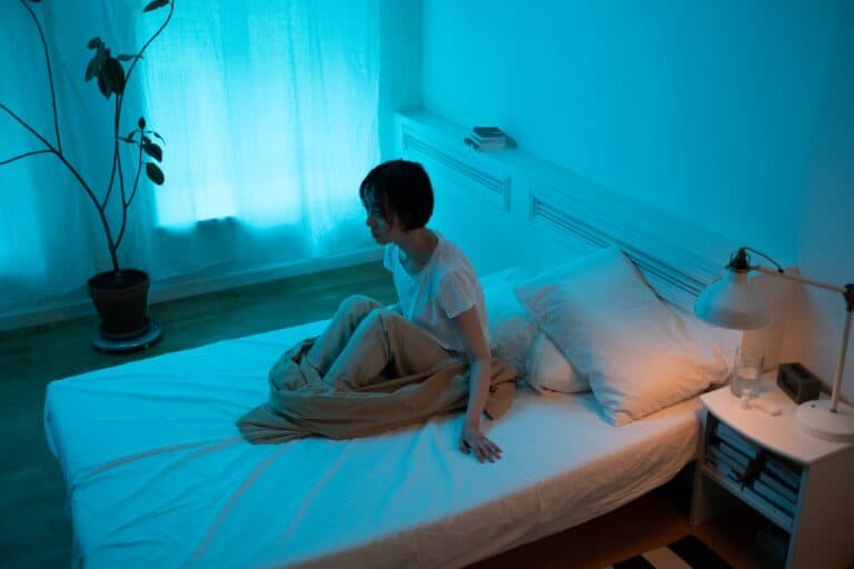 A Woman Sitting on Bed with Brown Blanket